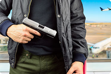 A man holding a gun in front of an airport.