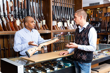 Two men buying firearms in a gun shop.