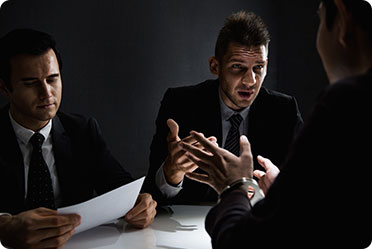 Three businessmen sitting at a table, one of them engaged in conversation.