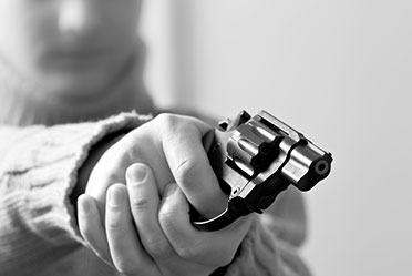 A monochrome image of a person gripping a firearm tightly, creating a stark and intense visual impact.