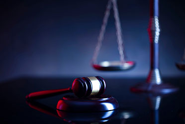 Gavel resting beside brass scales of justice in courtroom setting.