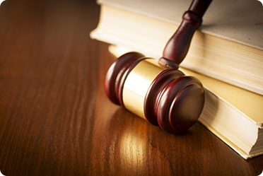 Gavel of judge is resting in front of books.