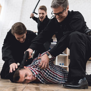 Three police officers holding a man down on the ground - Alex Kincaid Law