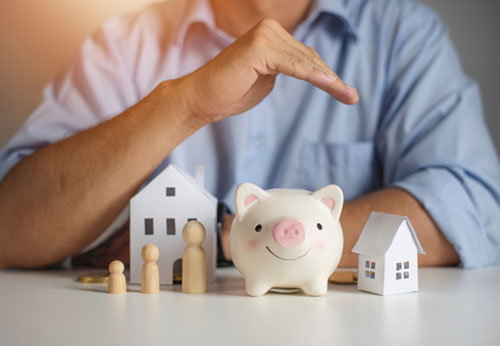 Hands protecting a model house, car, and family: insurance.