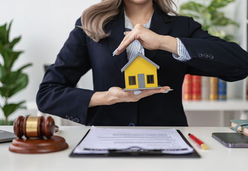 Lawyer protecting a model house with legal documents and gavel.