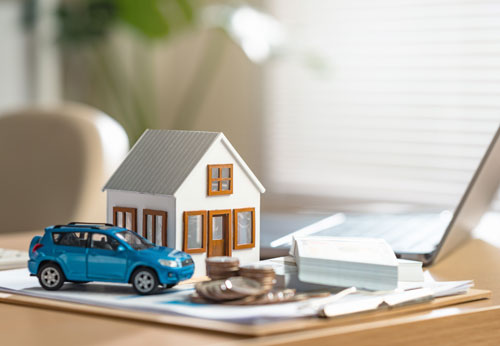 A miniature farm setup with a house, truck, coins, and barn, symbolizing estate planning for farmers.