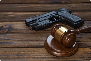 Handgun and judge’s gavel on a wooden table representing firearm law and legal defense - Alex Kincaid Law.