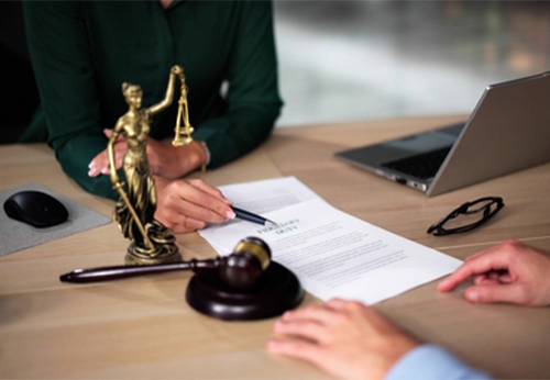 A lawyer and client review a contract near a Lady Justice statue.